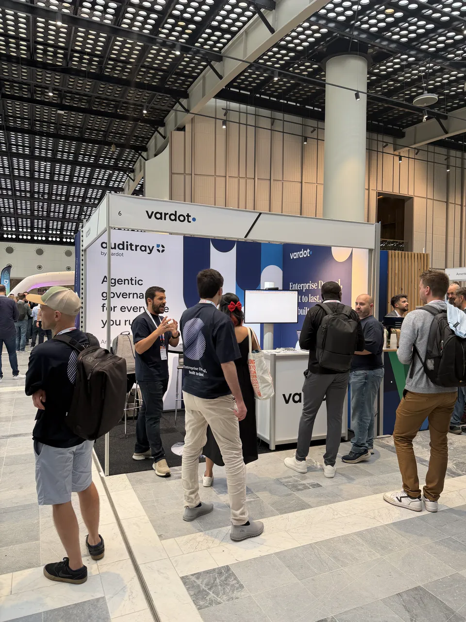 Visitors gathered at the Vardot booth while a team member talks them through Auditray.